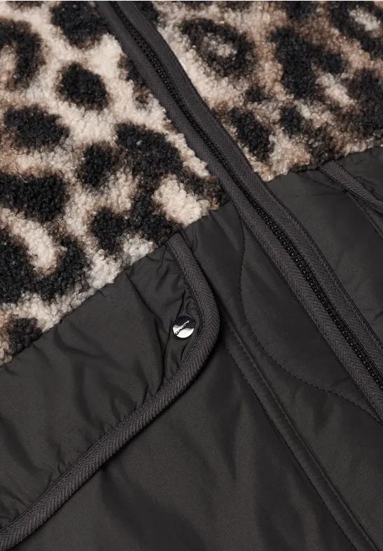 Gros plan d'une veste avec fourrure léopard, tissu noir, fermeture éclair et poche à pression.