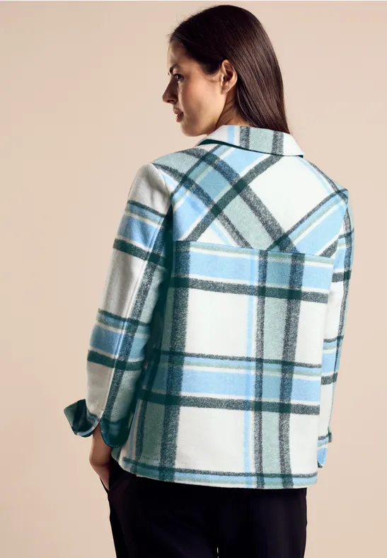 Vrouw met blauw-wit geruit jasje, gezicht van achteren.