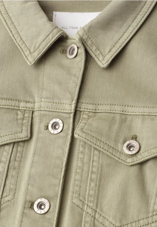 Nahaufnahme einer olivgrünen Jeansjacke mit Hemdkragen, Brusttaschen und silbernen Druckknöpfen.