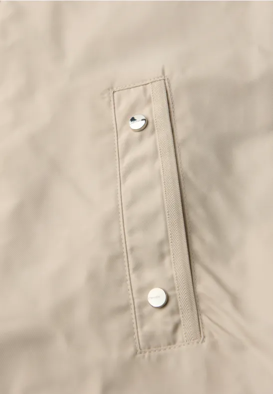 Beige Jacke mit schmaler Taschenklappe und silbernen Druckknöpfen