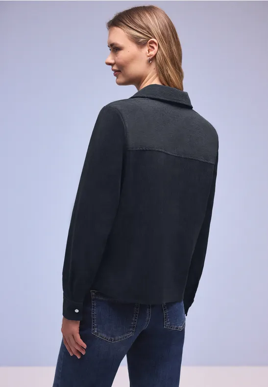 Persoon van achteren in een tweekleurig zwart-grijs jack en blauwe jeans.