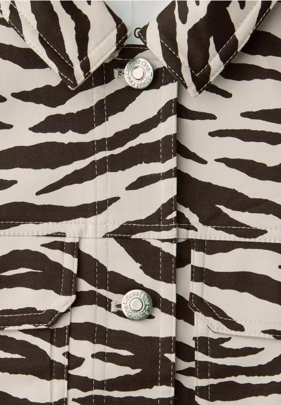Nahaufnahme eines Kleidungsstücks mit Zebra-Print und silbernen Knöpfen.