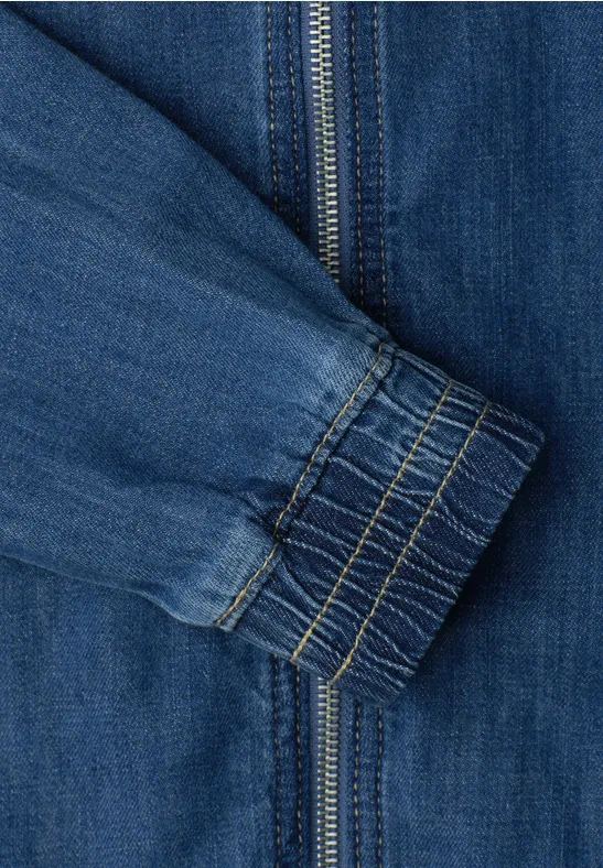 Nahaufnahme eines blauen Jeansjackenärmels mit Reißverschluss und elastischem Bündchen.