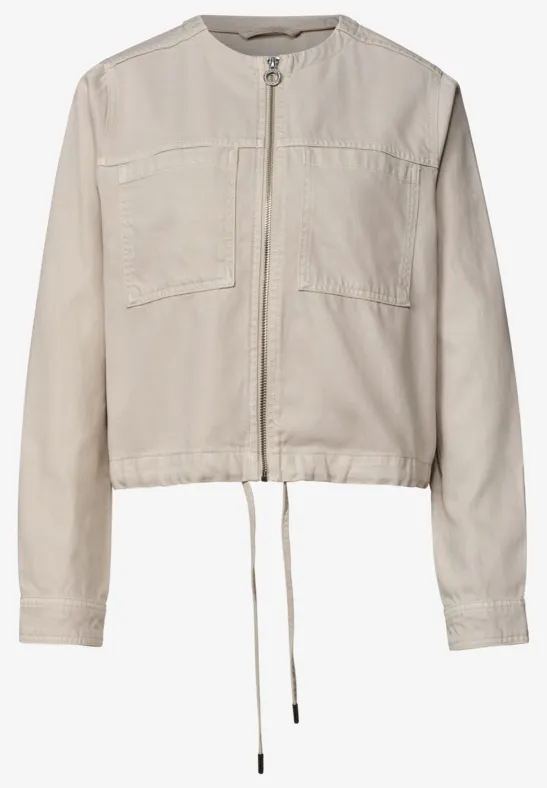 Veste légère beige clair avec fermeture éclair, manches longues, poches poitrine et cordon de serrage à la taille.