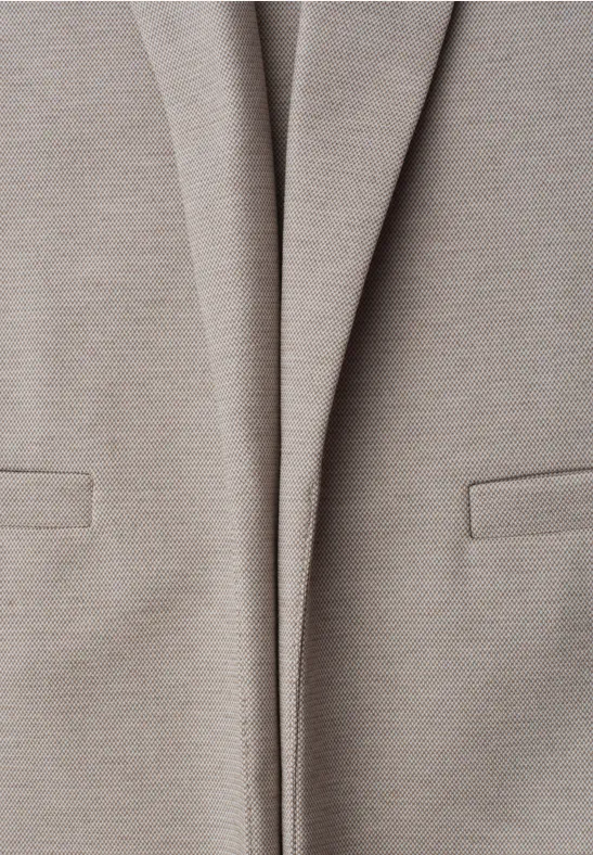 Close-up van een lichtbeige blazer met zakken aan de voorkant