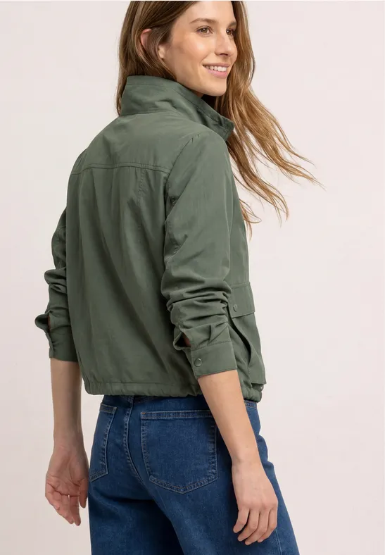 Rückenansicht einer Person in grüner Jacke und blauer Jeans.