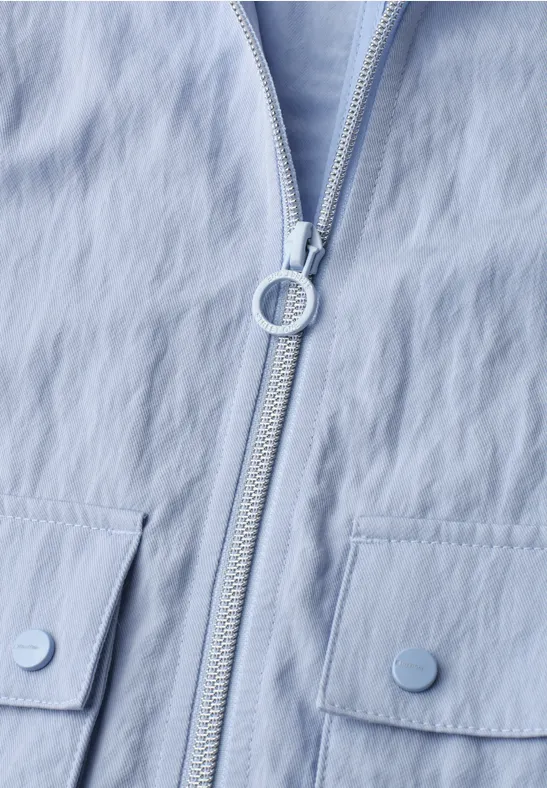 Hellblaue Jacke mit mittigem Reißverschluss, rundem Zipper-Anhänger und zwei aufgesetzten Klappentaschen
