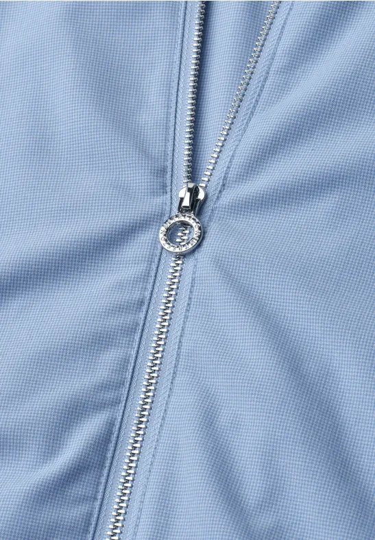 Close-up van een zilveren rits op lichtblauwe stof