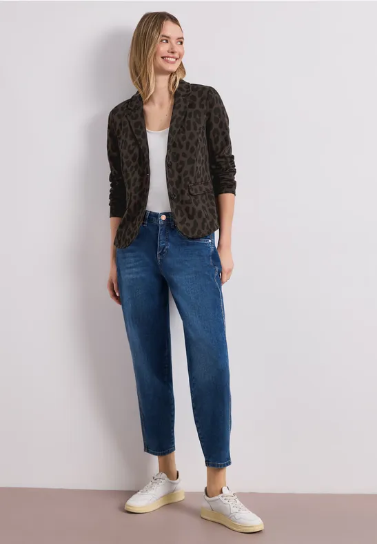 Personne porte un blazer léopard, un top blanc, un jean taille haute décontracté bleu et des baskets blanches.