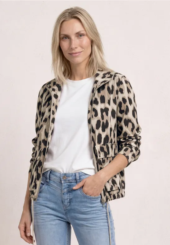 Person mit weißem T-Shirt, blauer Jeans und Leopardenjacke.