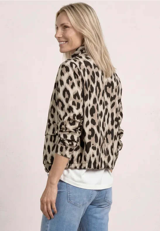 Blonde Frau von hinten in beiger Leopardenjacke, weißem Shirt und Jeans.