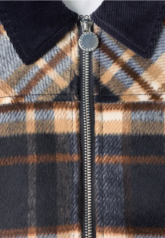 Close-up van een geblokte jas in bruin, blauw en wit met rits en een ribfluwelen kraag.