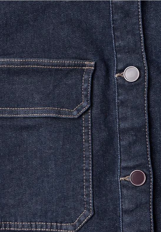 Nahaufnahme einer dunklen Jeansjacke mit aufgesetzter Tasche und Metall-Druckknöpfen.