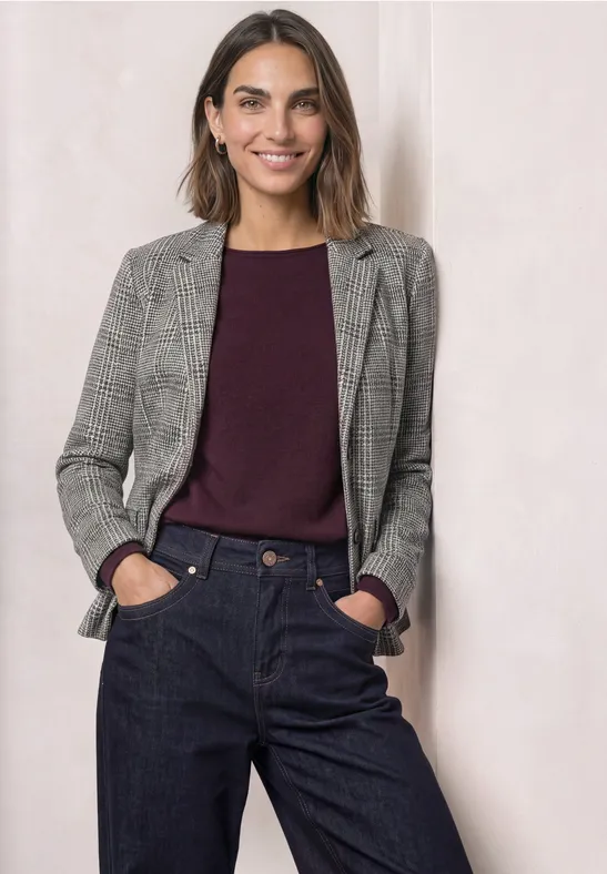 Femme en blazer gris, pull bordeaux et pantalon foncé.