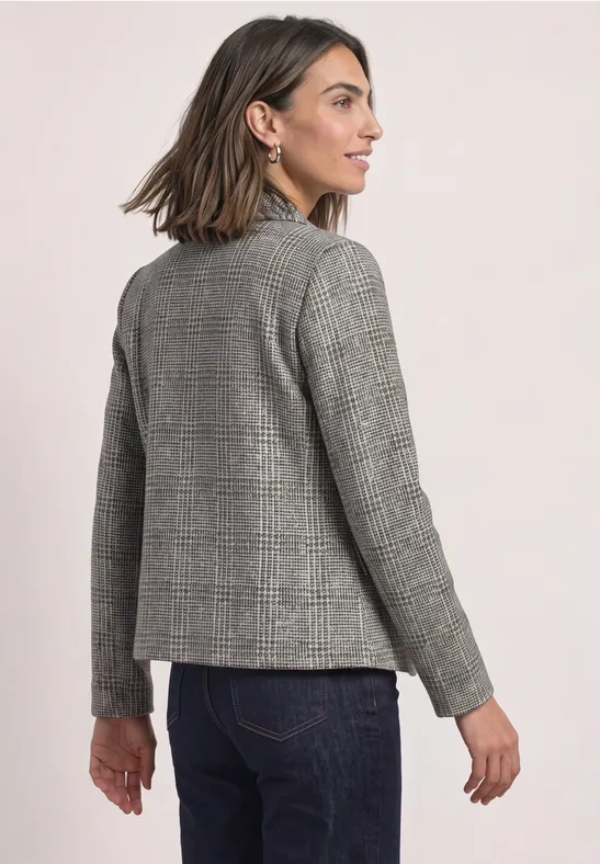 Femme vue de dos portant un blazer gris à carreaux et un jean bleu.