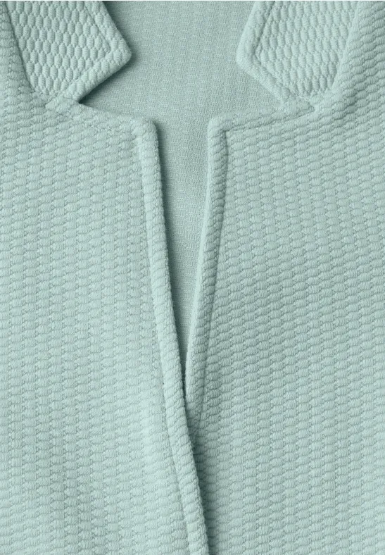 Gros plan d’un tissu tricoté vert menthe structuré avec col en V.