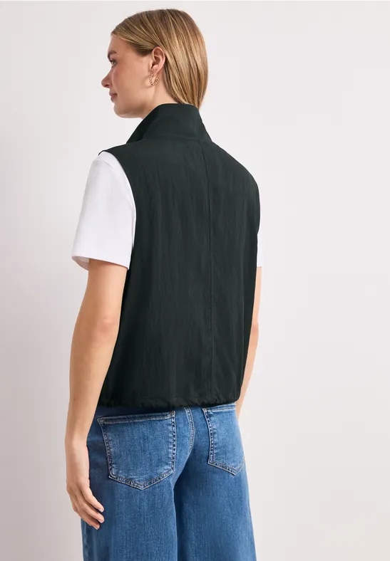 Vue arrière d’une personne portant un gilet noir, un T-shirt blanc et un jean bleu.