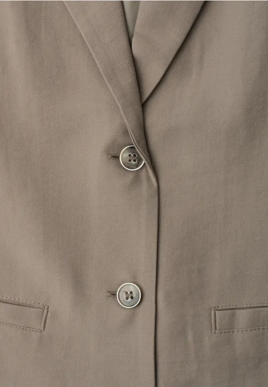 Gros plan d’un blazer taupe à revers cranté, deux boutons et poches à rabat.