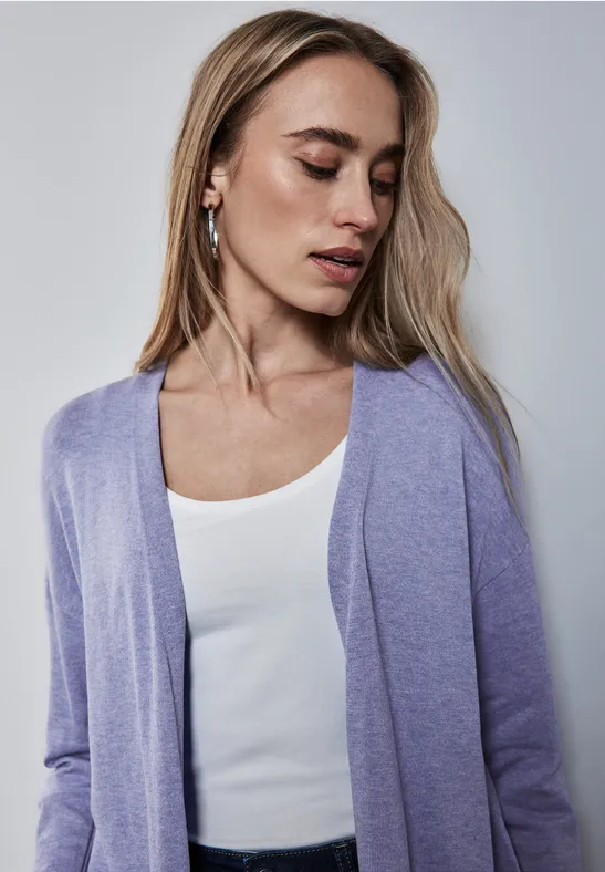 Frau mit langen Haaren trägt lila Cardigan und weißes Top.