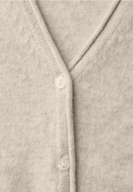 Nahe Aufnahme eines beigen, gestrickten Cardigans mit V-Ausschnitt und Knöpfen.