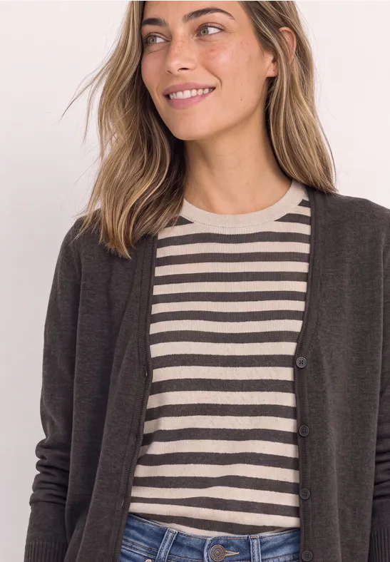 Eine lächelnde Frau trägt ein gestreiftes Shirt und einen dunklen Cardigan.