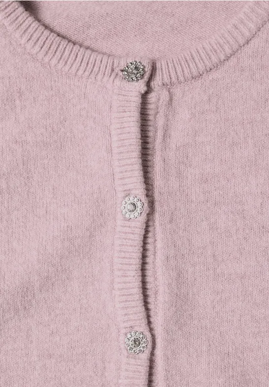 Close-up van een roze gebreid vest met geribbelde randen en fonkelende sierknopen.