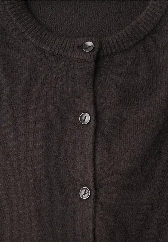 Close-up van een zwarte gebreide cardigan met ronde knopen en een ronde hals.