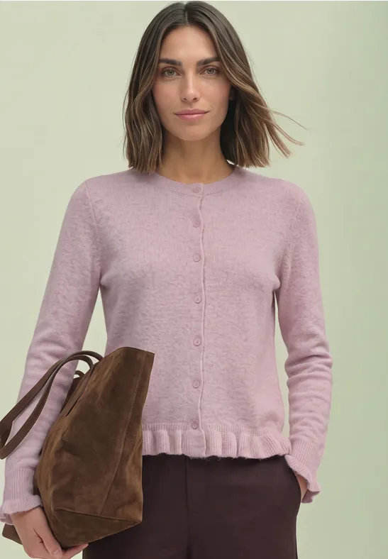 Vrouw in pastelroze cardigan met volantzoom, met een casual bruine tas.