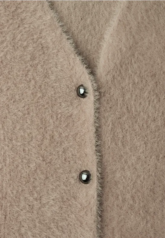Beige, pluizige gebreide cardigan met twee donkere knopen, zacht materiaal.