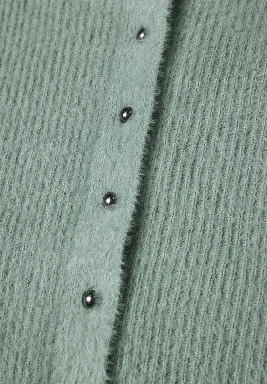 Maille duveteuse vert sauge avec une rangée verticale de pressions argentées.
