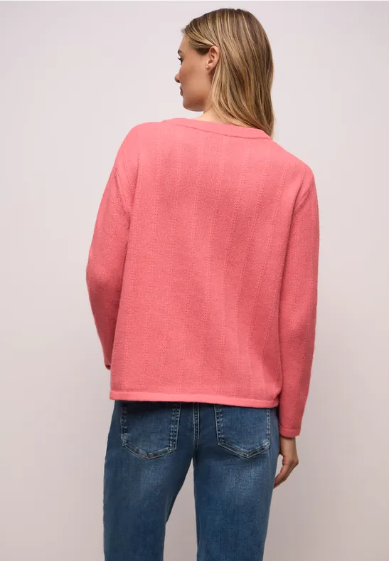 Person von hinten in pinkem Pullover und Jeans, lange blonde Haare.