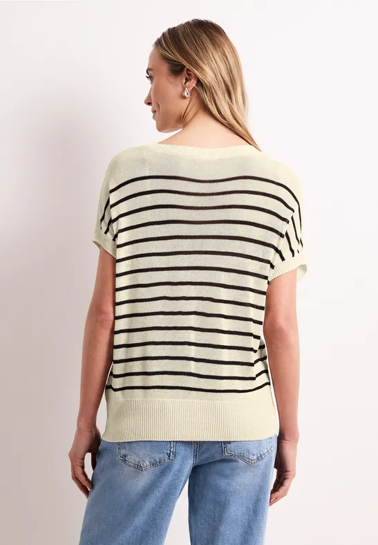 Frau von hinten in hellem, lockerem Strickshirt mit schwarzen Streifen und Jeans.