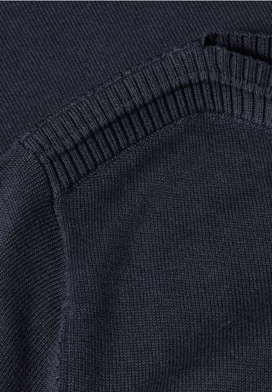 Nahaufnahme eines dunkelblauen Strickpullovers mit einer aufgesetzten Tasche und Rippstrickbündchen.