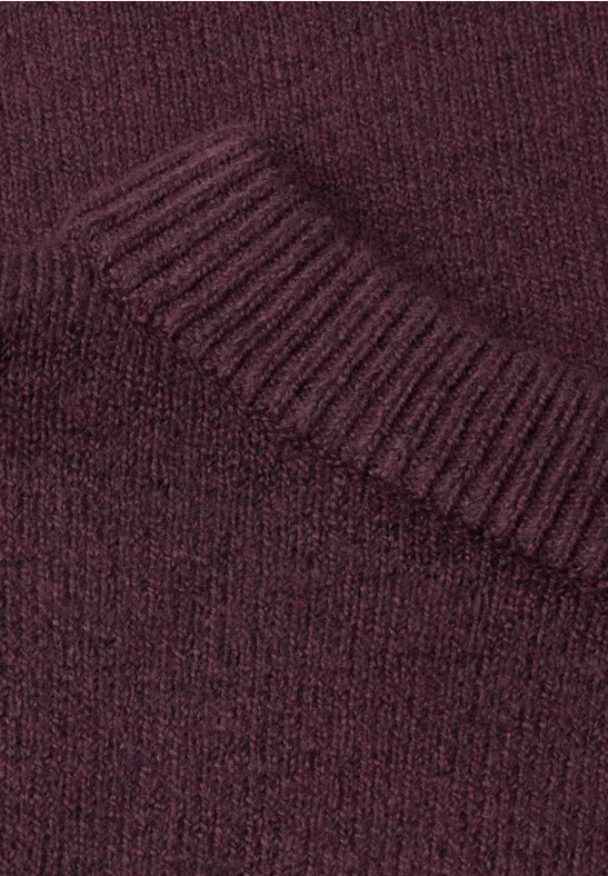Nahaufnahme eines burgunderroten Strickpullovers mit Rippenstrick am Kragen.