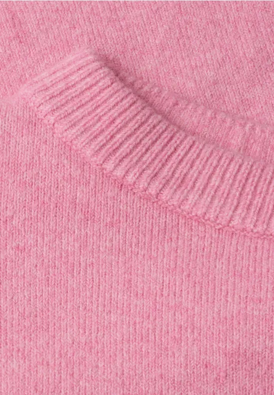 Gros plan sur un pull en maille rose pastel à la texture douce et finement tricotée.