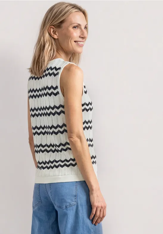 Vue de dos d'une personne portant un gilet en tricot à motifs et un jean sur fond neutre.