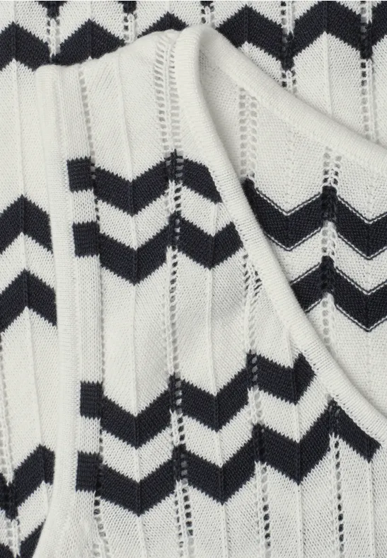 Gros plan d'un top en maille blanc à motifs chevrons noirs
