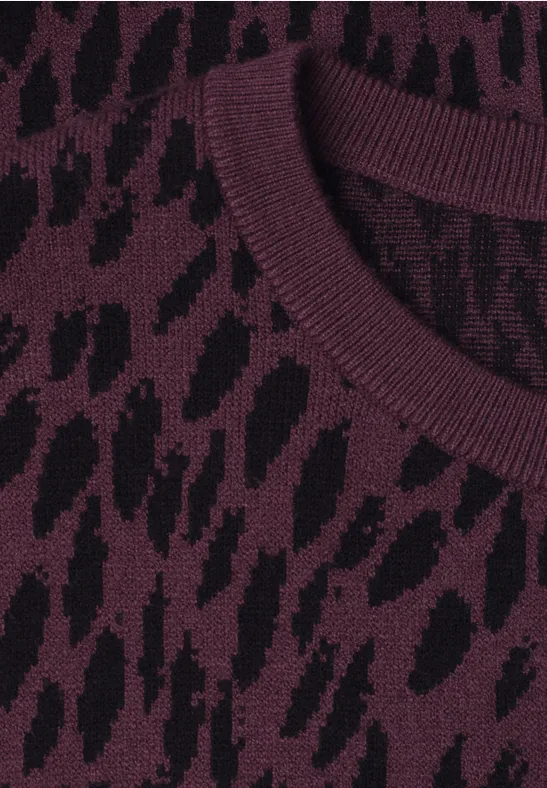 Nahaufnahme des Rundhalsausschnitts eines Strickpullovers mit lila-schwarzem Tiermuster.