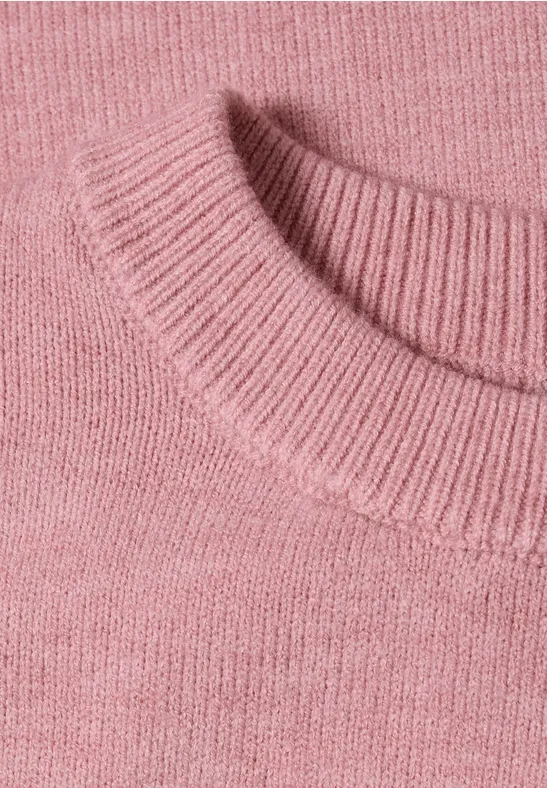 Gros plan d'un col de pull rose en maille fine, texture chaleureuse.