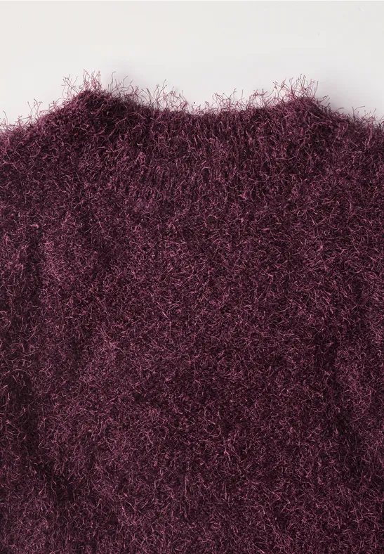 Nahaufnahme eines flauschigen, weinroten Strickpullovers.