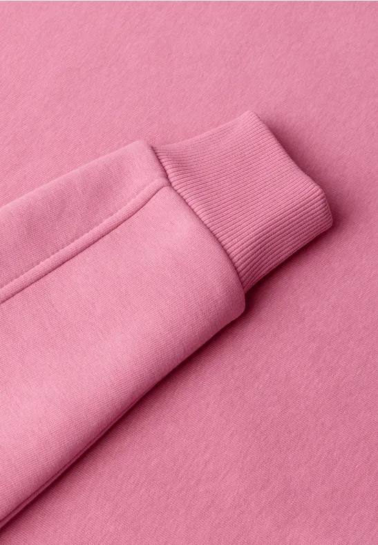 Nahaufnahme eines rosa Sweatshirtärmels mit Bündchen.