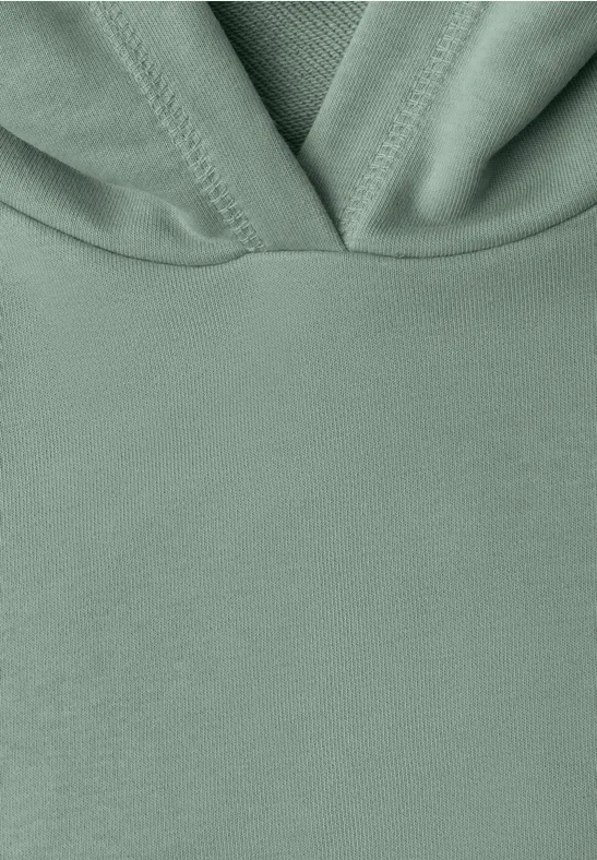 Vue rapprochée d’un sweat à capuche vert clair, tissu doux et minimaliste.