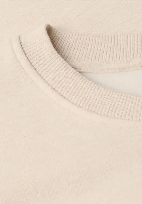 Gros plan sur le col côtelé d’un t-shirt beige