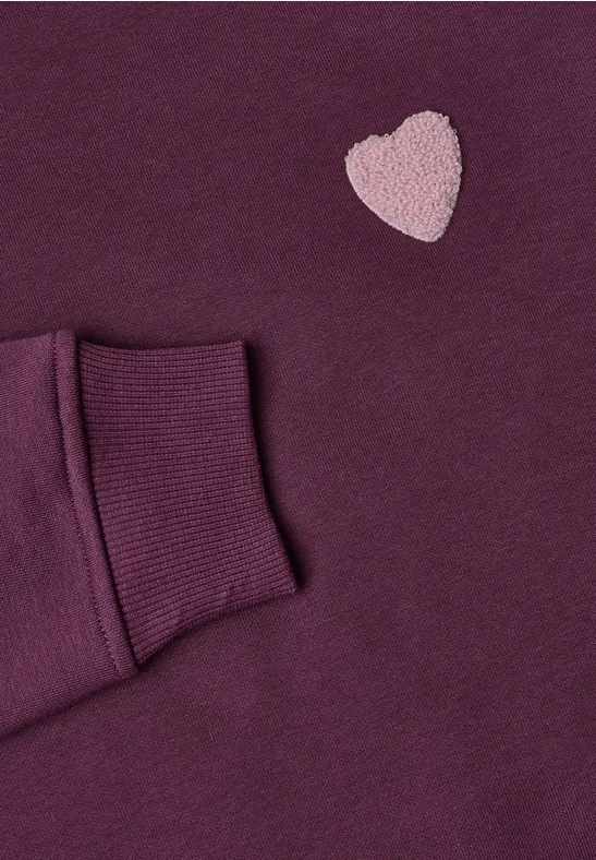 Manche de sweat violet avec un cœur rose brodé sur un tissu doux