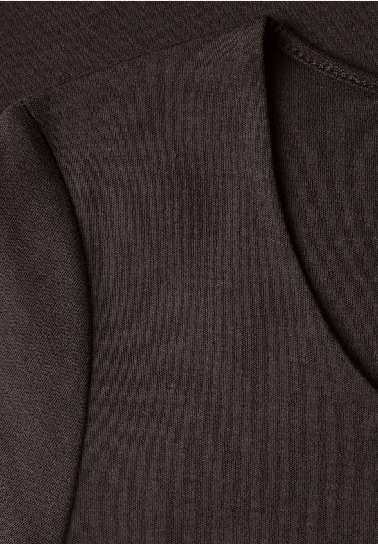 Nahaufnahme eines dunkelbraunen T-Shirts mit V-Ausschnitt und sichtbarer Schulternaht.