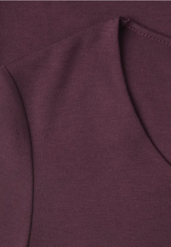 Nahaufnahme eines burgunderfarbenen Sweatshirtstoffs mit sichtbarer Naht