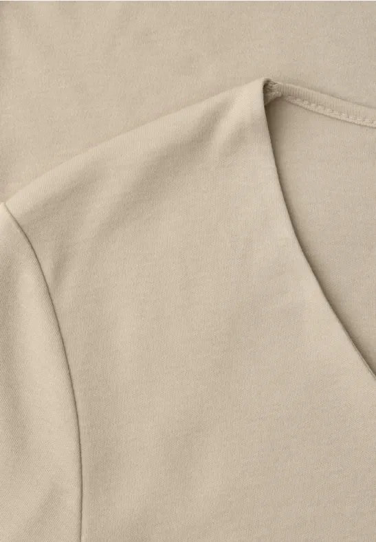 Close-up van een lichtbeige katoenen T-shirt met V-hals.