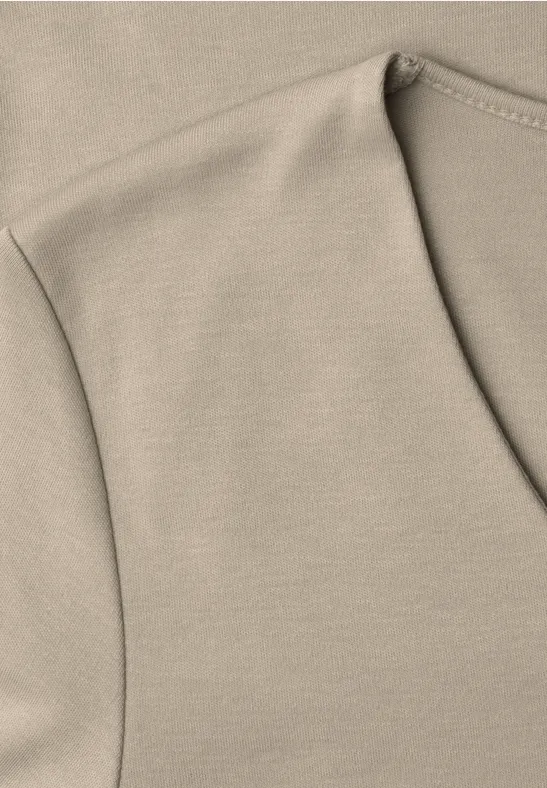 Gros plan d’un T-shirt beige aux coutures visibles près de l’encolure.