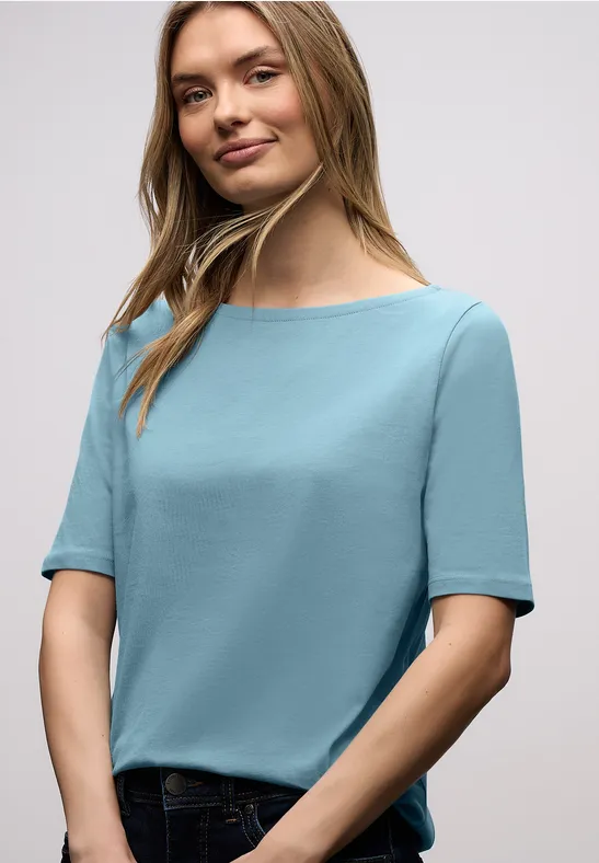 Femme en haut bleu clair et jean sur fond blanc
