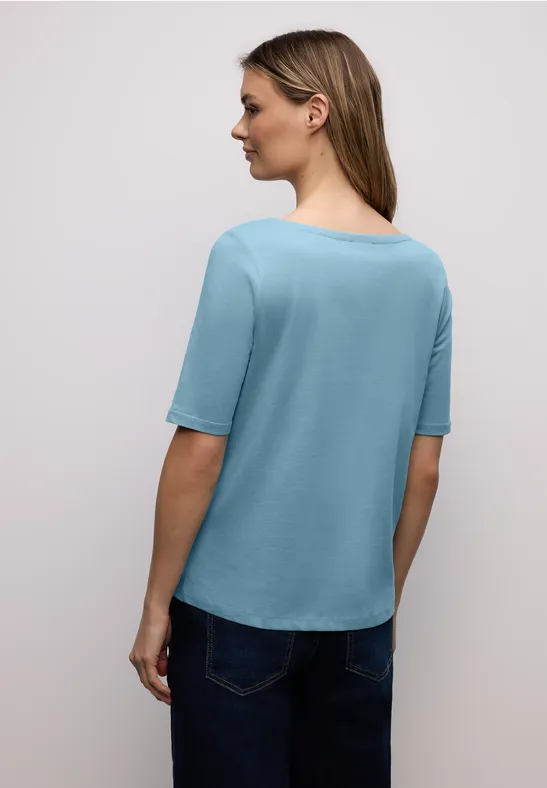 Femme vue de dos avec un T-shirt bleu ciel et un jean foncé